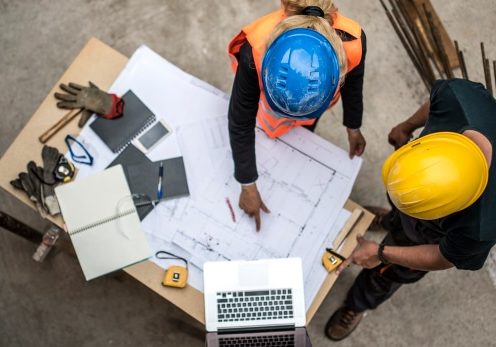 Two architects examining the blueprints on construction site